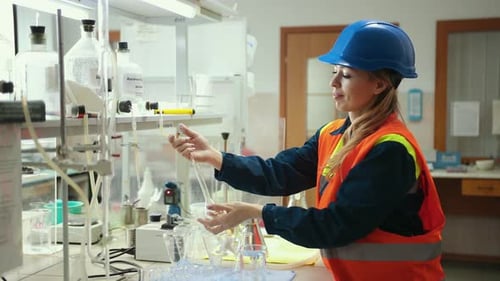 Female Scientist Pours Liquid Through Glassware in Lab