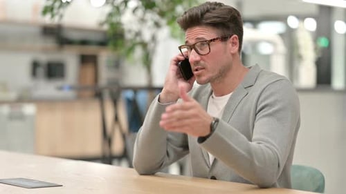 Cheerful Middle Aged Man Talking on Smartphone in Office