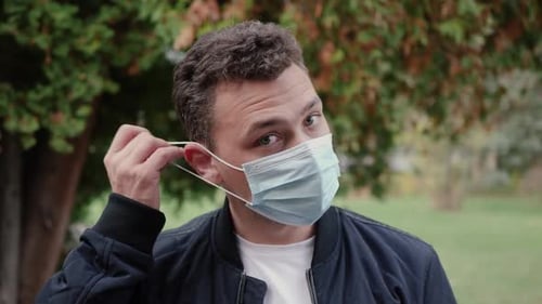 Man Removing Surgical Mask in Park
