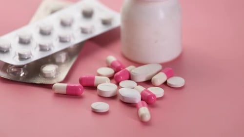 Close Up of Colorful Pills Spilling on Pink Background