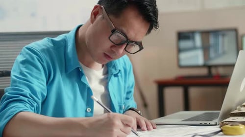 Close Up Of Asian Man Engineer With A Laptop Drawing Blueprint At The Office