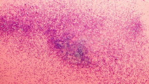 Pouring Glitter on a Pink Background