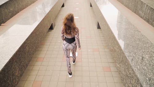 Athletic Girl in a sports jumpsuit gracefully goes through the city. Slow motion. Top view