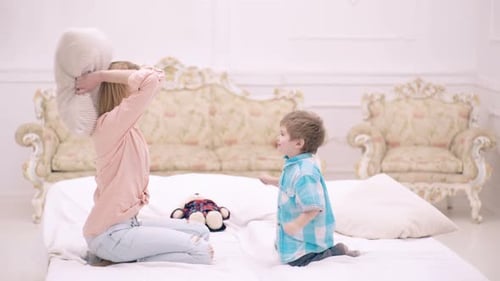 Mother and Child Play Pillow Fight on Bed