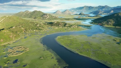 Bends and curves of blue river flowing through green valley toward distant mountains.