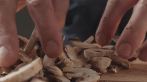Der junge Koch in Restaurantuniform arbeitet in der Küche und hält Pilze