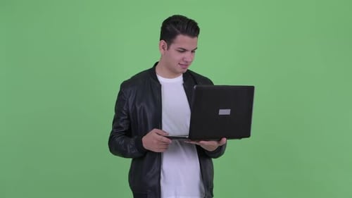 Young Adult Uses Laptop on Green Screen