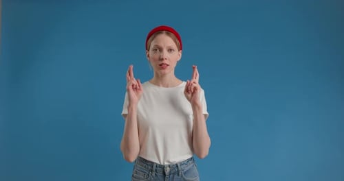 Woman With Fingers Crossed Against Blue Background