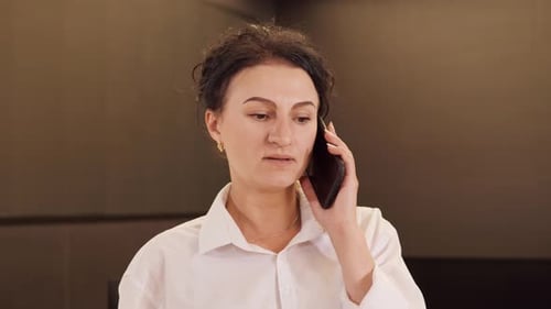 Focused Confident Business Woman Talking on Smartphone in Office Interior