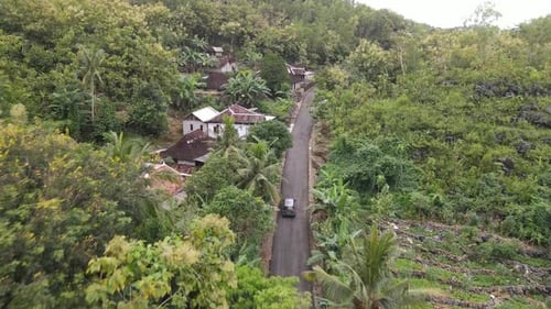 Aerial view of a car riding on the small road through village on the countryside in Indonesia