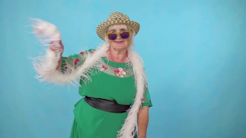 Enthusiastic Senior Woman Dances with White Feather Boa