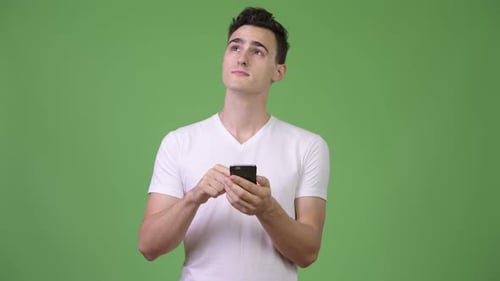 Young Man Uses Smartphone and Looks Up