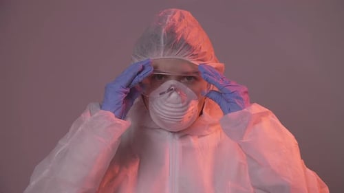 Professional Female Doctor in Mask Standing in Hospital Room Putting Glasses On. Health Care Concept