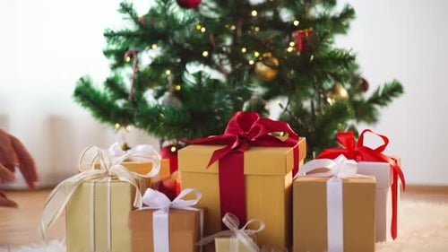 Placing Gifts Beneath Sparkling Christmas Tree at Home