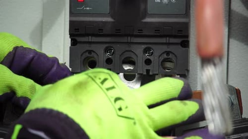 Closeup View of Electrician Installing Wires Cables Into a Electricity Power Shield Fuse Box an