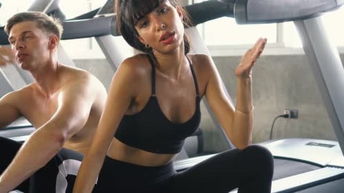 Tired Caucasian Couple Sweating and Feeling Hot After Exercising on Treadmill at the Gym