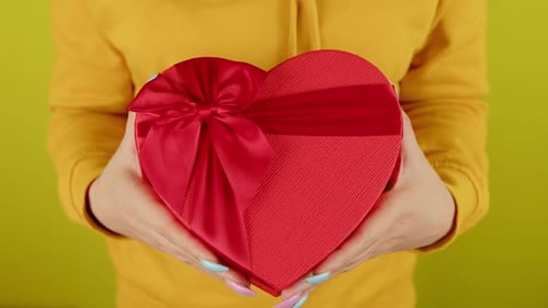 Hands Holding Red Heart Shaped Gift