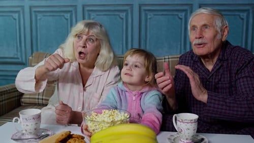 Family Watching TV with Grandparents and Popcorn