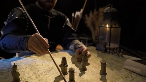 Medieval Commander Planning Battle with Map and Pieces