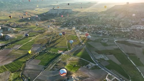 Hot air balloons fly over the mountainous landscape of Cappadocia, Turkey.