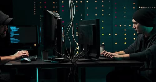 Two People Typing on Computers in Server Room