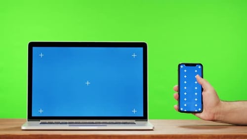 Laptop and Smartphone with Blue Chroma Key on Green Background Closeup