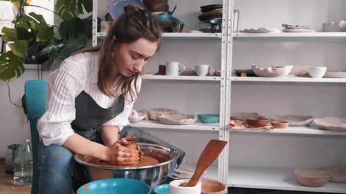 Potter in Apron Making Vase on Potter's Wheel in Workshop