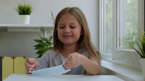 Little Girl Puts on a Preventive Medical Mask Indoor Concept of Home Quarantine