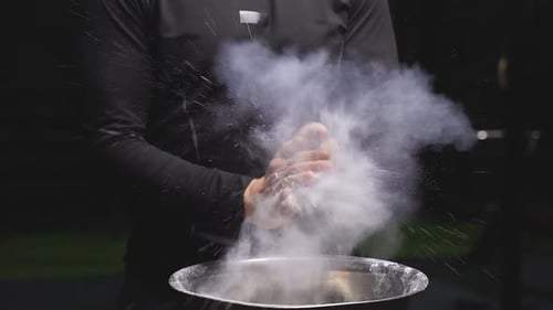 Muscular Man Claps Hands with White Powder