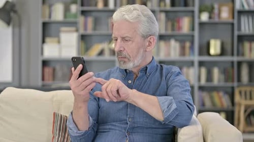 Senior Man Using Smartphone in Living Room