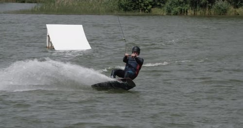 Wakeboarding in a Lake Near the Forest, Adult Man Surfs on the Water, Ride on a Wakeboarding Board
