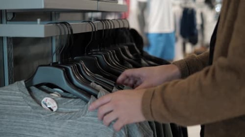Man Chooses Sports Clothes in a Store Shopping Mall Young Student Casual Clothing Buy Checkout