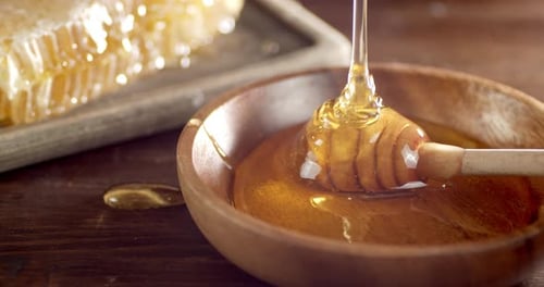 Fresh Honey Flows Into the Wooden Plate.