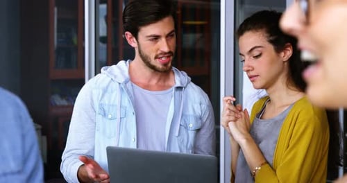 Young Adults Collaborating on Laptop in Workplace