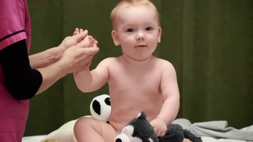 Masseuse Gently Massaging Adorable Baby's Arm Indoors