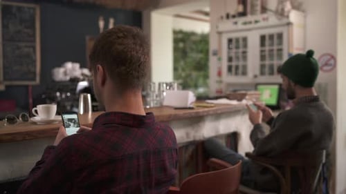 Young Men Use Phones in Coffee Shop