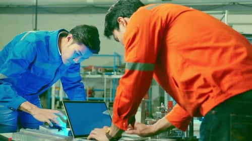Male Asian engineer professional having a discussion standing by the machine in the factory
