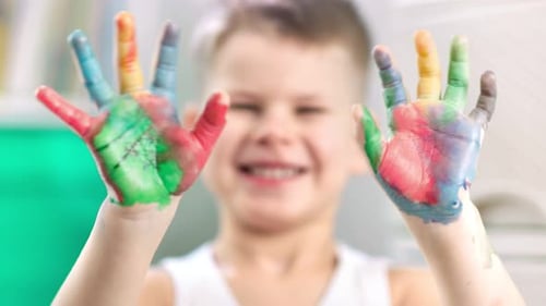 Boy Smiling with Colorful Painted Hands