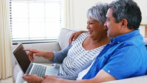 Senior Couple Laughing Using Laptop at Home