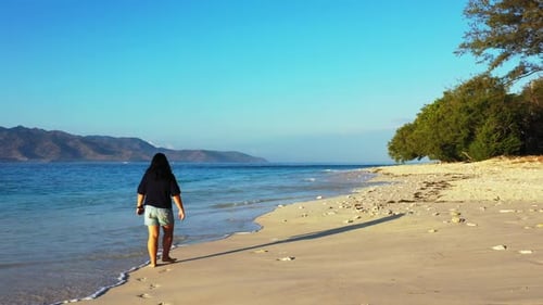 Single female tanning on tropical seashore beach lifestyle by blue green lagoon and white sand backg