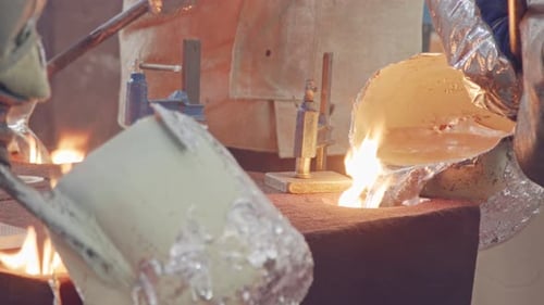 Workers in a foundry pouring liquid Aluminum to a sand cast