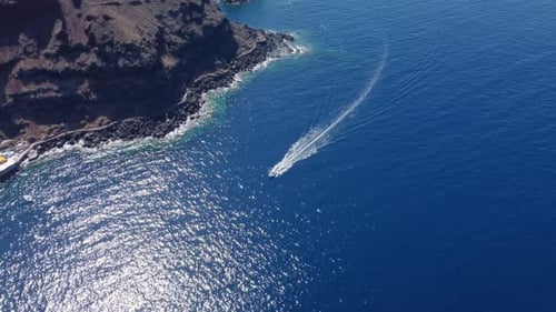 Aerial view of floating boat on blue sea at sunny day. Fast boat on the sea surface. Seascape from d