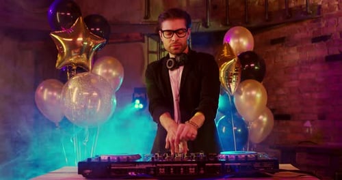Young Adult DJ Mixing Music at Party with Balloons