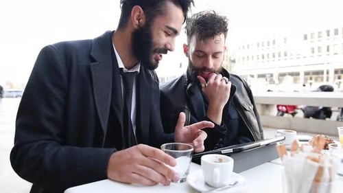 Two young bearded business man sitting in a bar using tablet