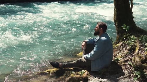 Handsome Man Is Resting on River Shore in Forest Alone