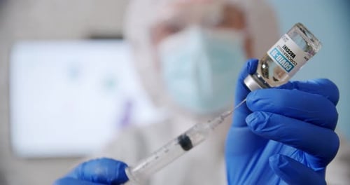 Blured Doctor's Hand Holds a Syringe and a Vaccine Bottle at the Hospital