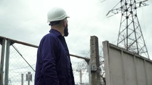 Engineer in Special Uniform Standing with Tablet Near Power Station. Energy Efficiency Conception