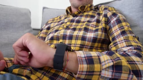 Man on Couch Relaxing with Phone and Watch