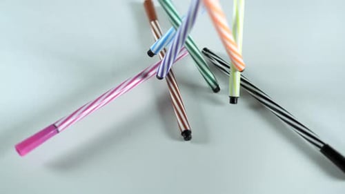 Colorful Striped Markers Falling onto Gray Background