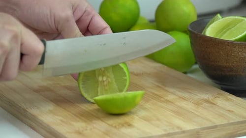 Cutting Fresh Green Lime into Segments on Board
